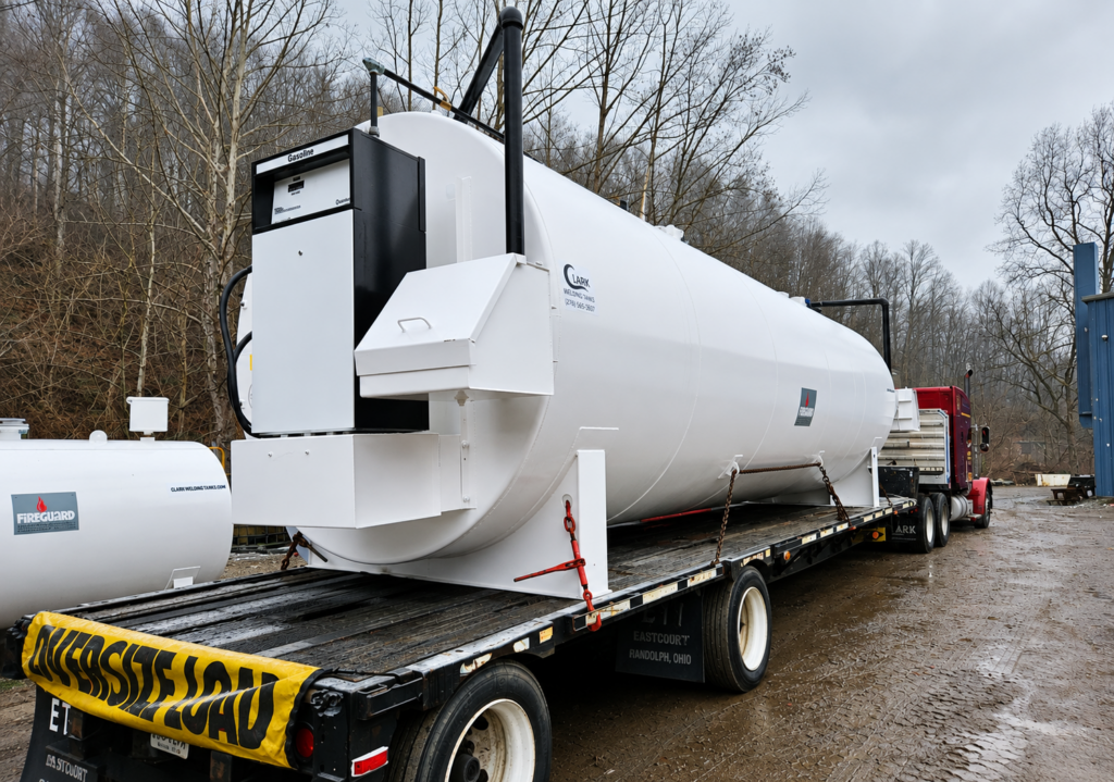 Horizontal steel tank with dispenser cabinet secured to a transport trailer